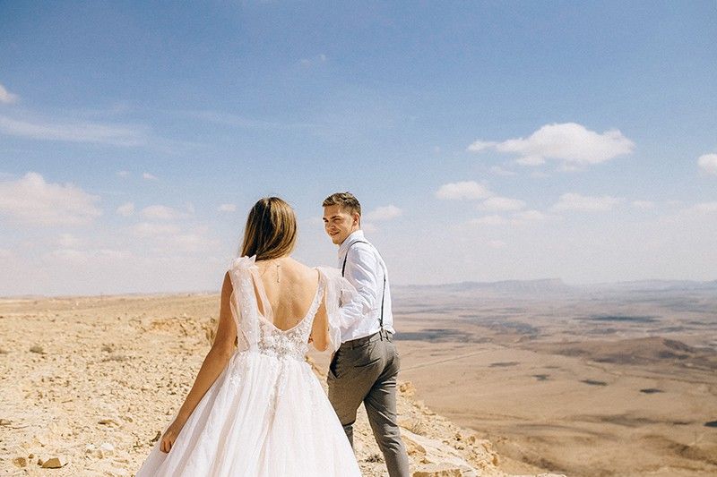 Hochzeitspaar hält Händchen in der Wüste
