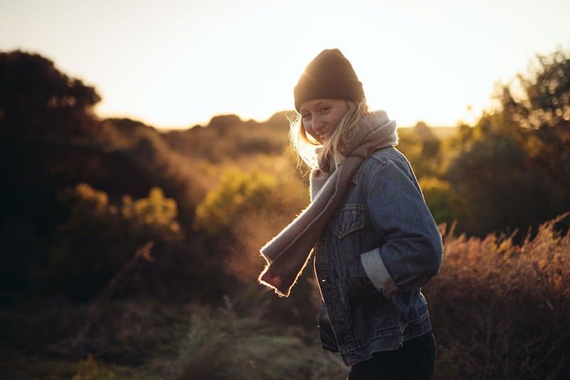Lächelnde Frau, die bei Sonnenuntergang auf dem Feld spaziert