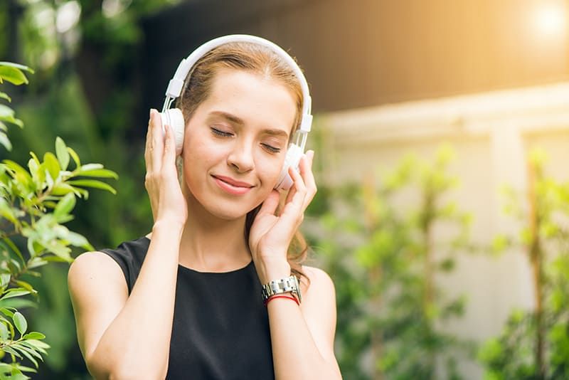 Frau hört mit geschlossenen Augen Musik über Kopfhörer