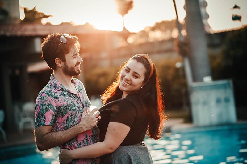 glückliches Paar, das sich umarmt, während es in der Nähe des Pools steht