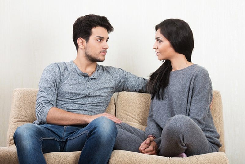 Junges Paar redet, während es zusammen auf dem Sofa sitzt