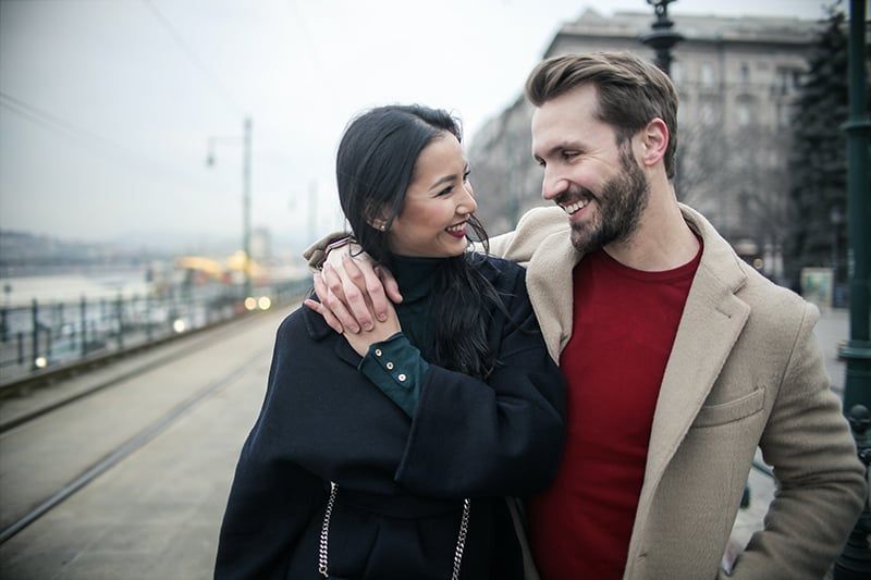 Lächelndes Paar, das sich beim Gehen auf dem Bürgersteig anschaut