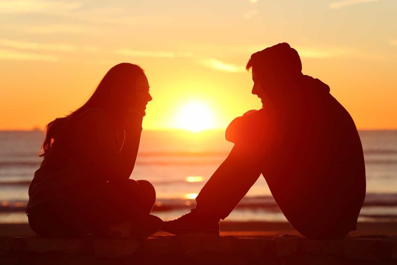 Ein Mann und eine Frau sitzen bei Sonnenuntergang und reden