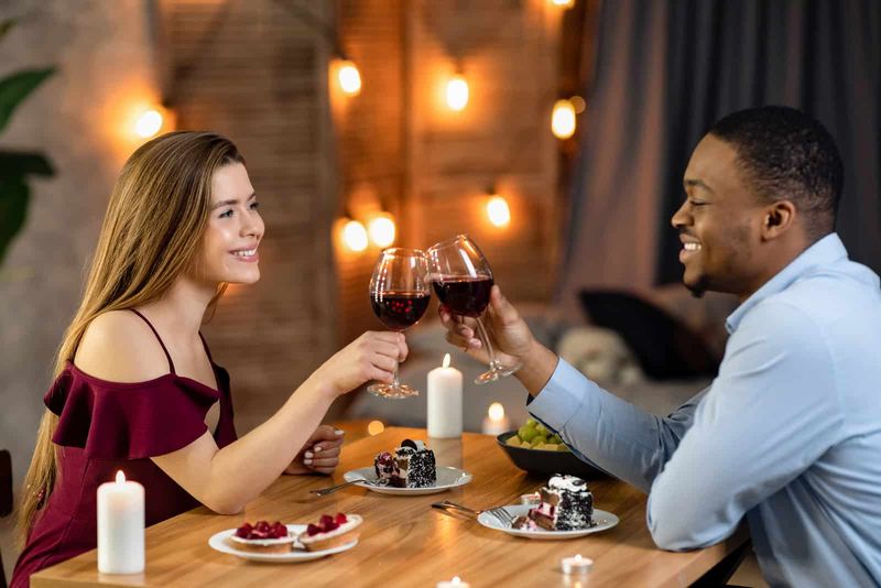 Ein Mann und eine Frau sitzen an einem Tisch und stoßen mit Wein an
