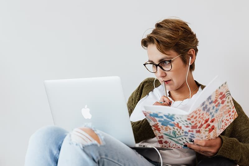 Konzentrierte Frau benutzt Laptop und macht sich Notizen