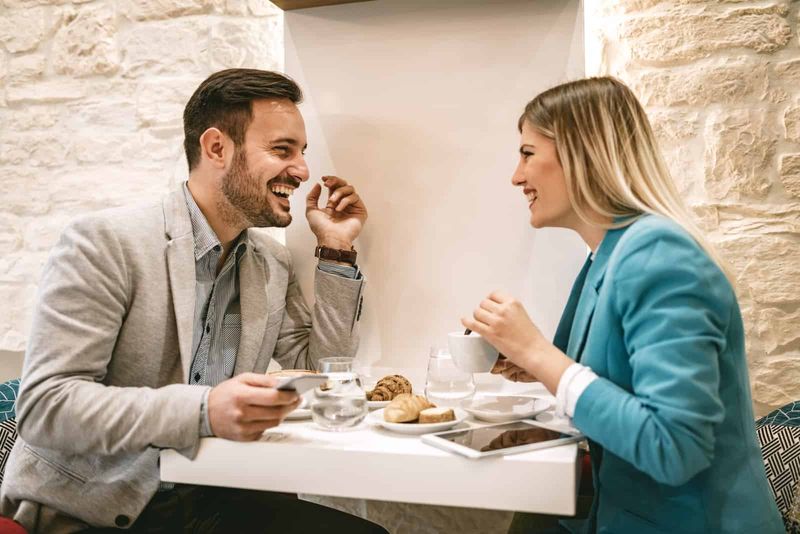 Ein lächelnder Mann und eine lächelnde Frau sitzen an einem Tisch und unterhalten sich