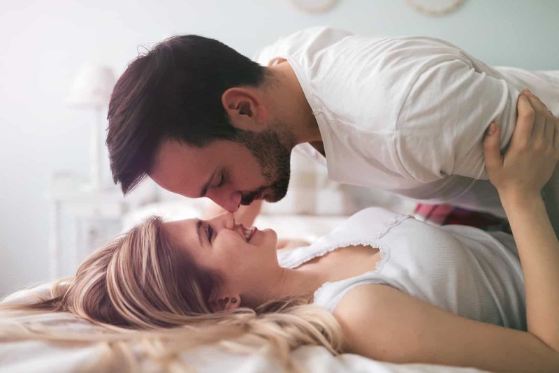 Ein Mann und eine Frau küssen sich im Bett
