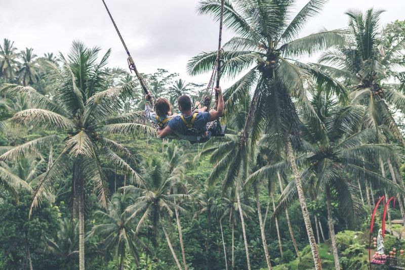 Mann und Frau an der Seilrutsche in der Nähe von Kokospalmen