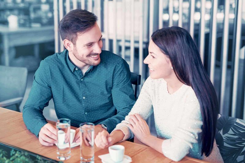 Ein lächelnder Mann und eine lächelnde Frau sitzen nebeneinander und unterhalten sich