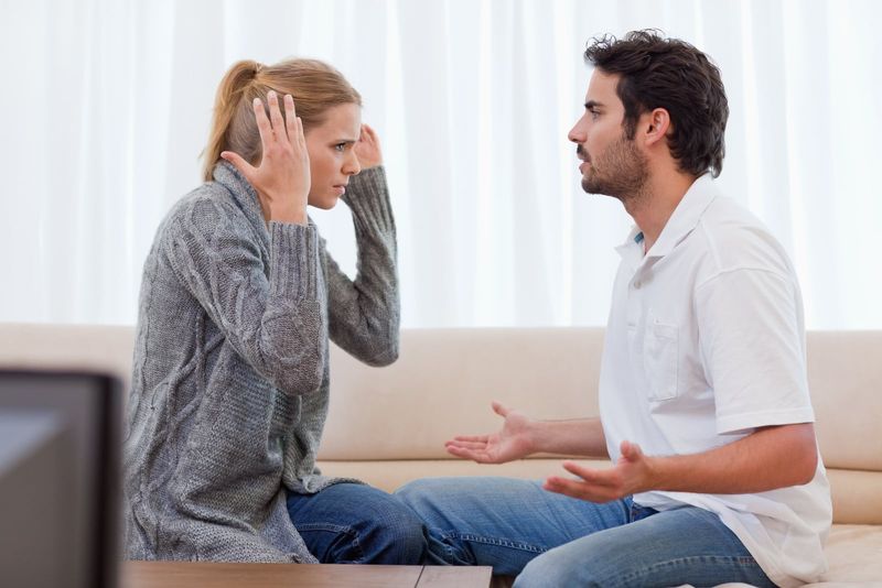 Wütende blonde Frau streitet mit Mann auf der Couch