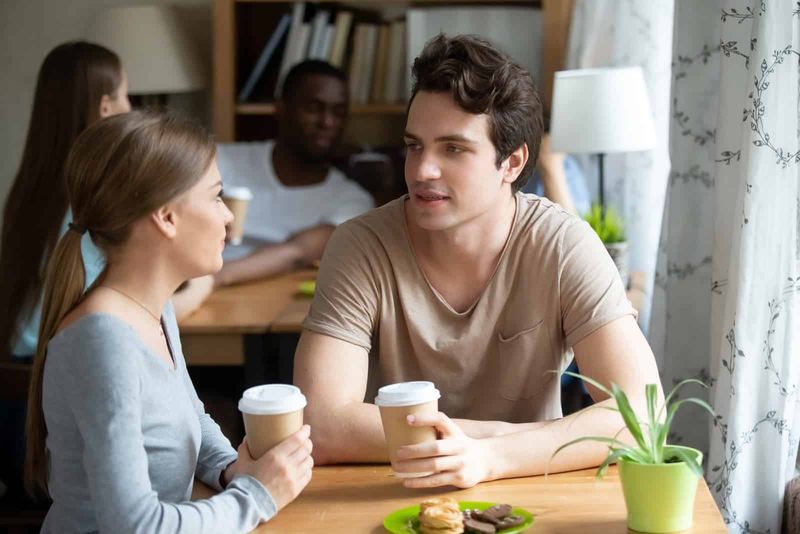 Ein Mann und eine Frau sitzen an einem Tisch, trinken Kaffee und reden