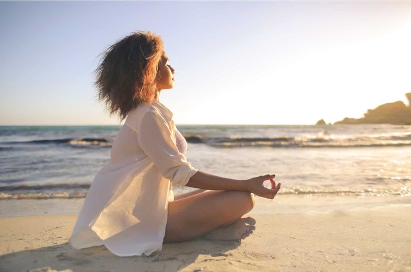 Frau meditiert am Strand in Suset