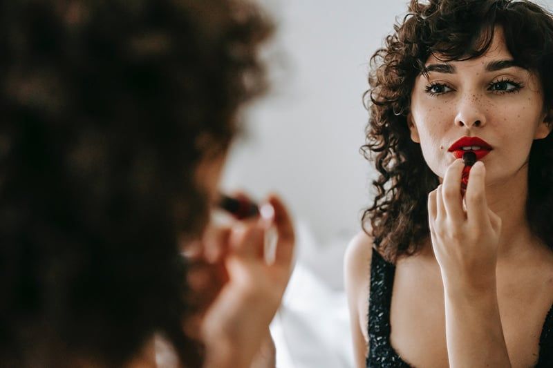 Selbstbewusste Frau, die vor dem Spiegel einen Lippenstift aufträgt