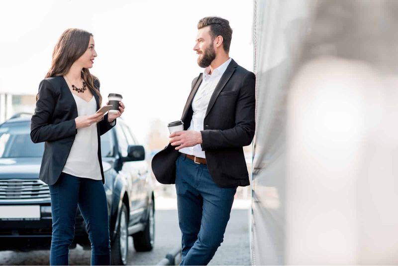 Ein Mann und eine Frau stehen auf der Straße, halten Kaffee in ihren Händen und unterhalten sich