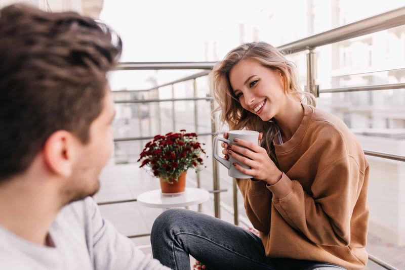 Ein Mann und eine Frau unterhalten sich auf dem Balkon beim Kaffee