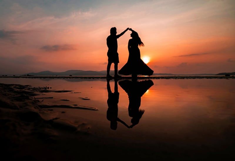Paar tanzt bei Sonnenuntergang am Strand