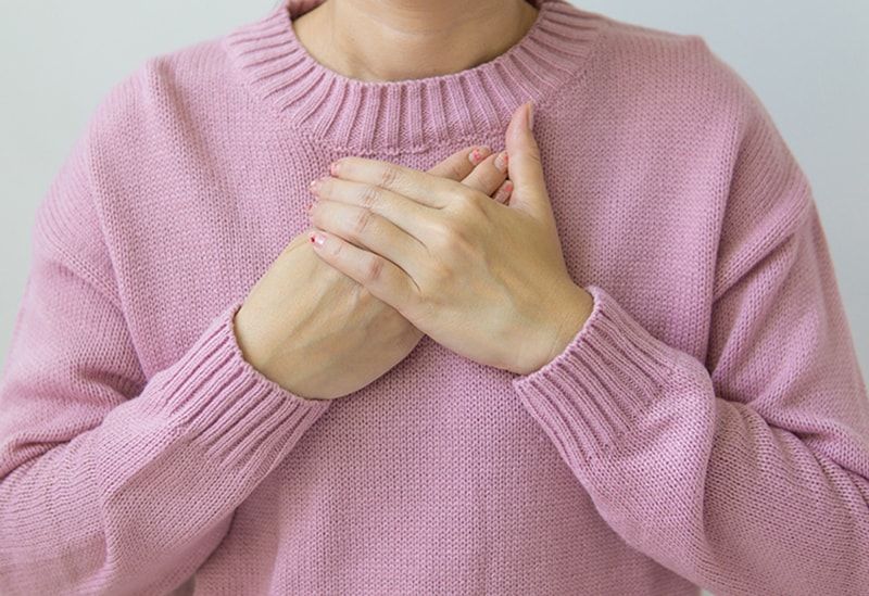 Frau trägt einen rosa Pullover mit den Händen auf der Brust