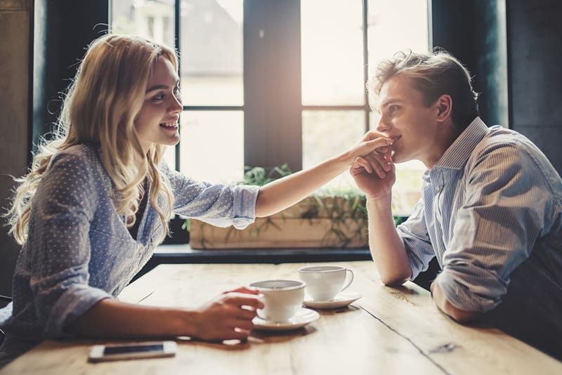 Mann küsst einer Frau bei einem Date im Café die Hand