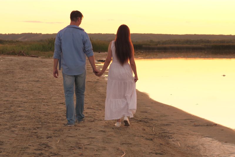 Ein Mann und eine Frau gehen Händchen haltend am Strand entlang