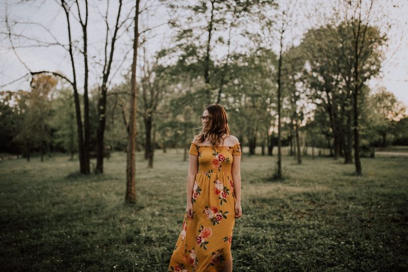 Frau im gelben Blumenkleid steht im Wald