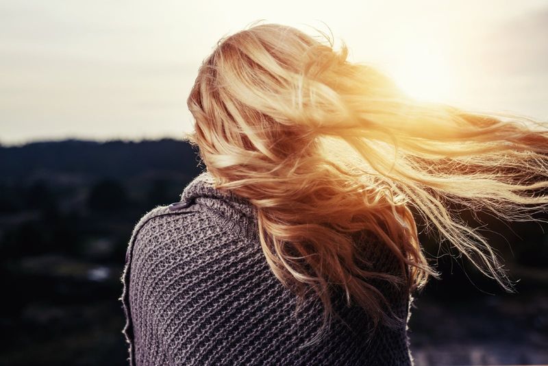Frau im grauen Pullover, die während des Sonnenuntergangs im Freien steht