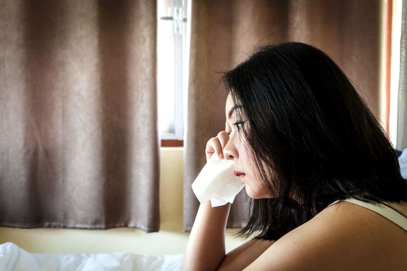 Eine deprimierte asiatische Frau weint zu Hause