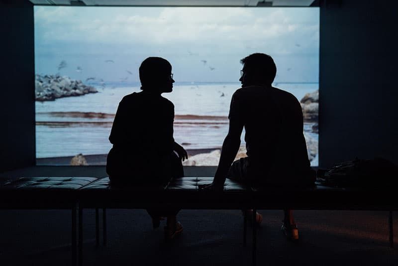 Silhouette eines Mannes und einer Frau, die sich mit Blick auf das Meer unterhalten