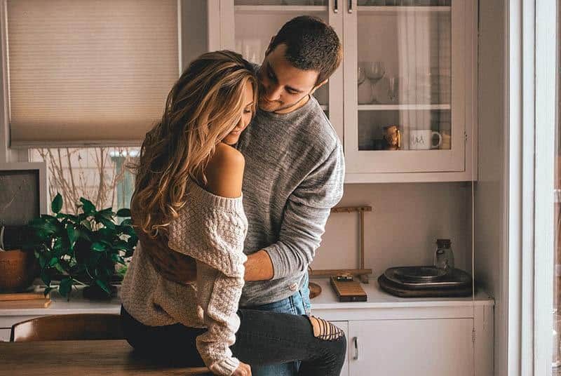 Mann umarmt Frau in der Küche zu Hause