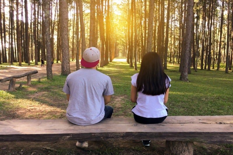 Mann und Frau sitzen auf einer Bank im Wald