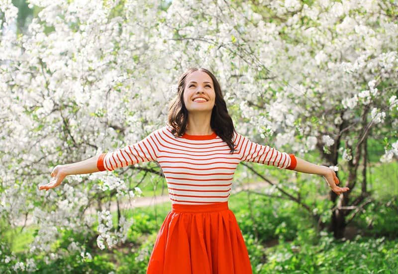 Schöne glückliche junge Frau genießt den Duft in einem blühenden Frühlingsgarten