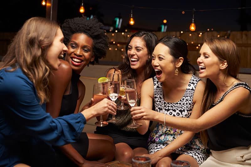 Eine Gruppe Freundinnen genießt den Abend in der Bar auf dem Dach