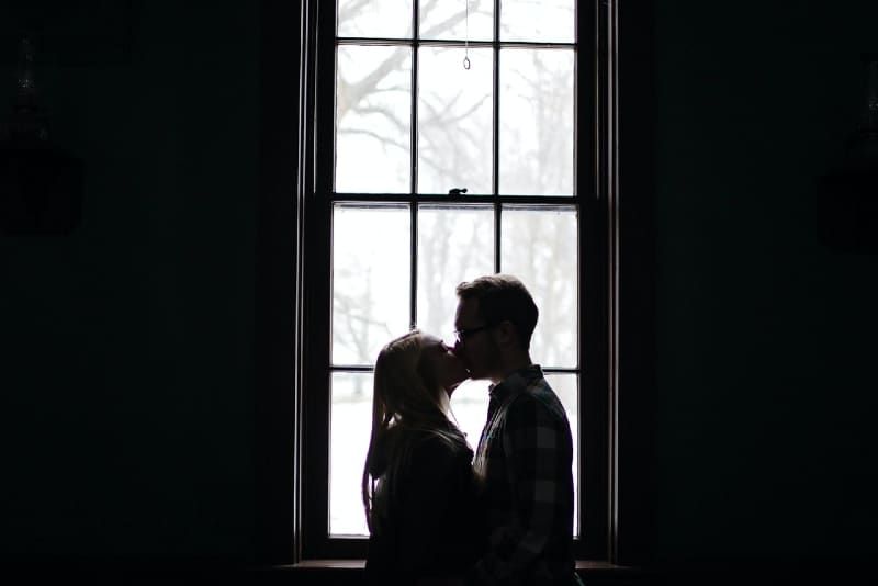 Mann und Frau küssen sich, während sie am Fenster stehen
