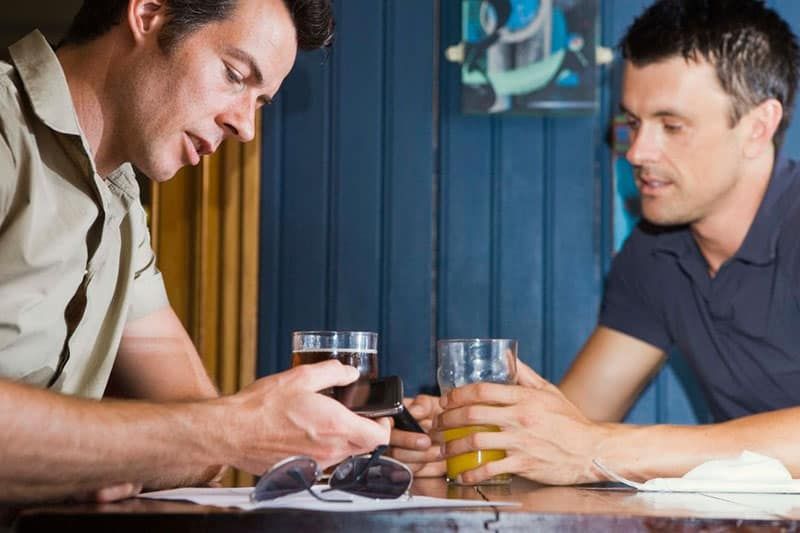 2 Männer trinken Bier, während sie sich auf einem Tisch unterhalten