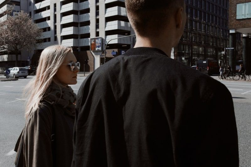 Blonde Frau mit Sonnenbrille und Mann, der auf die Straße blickt