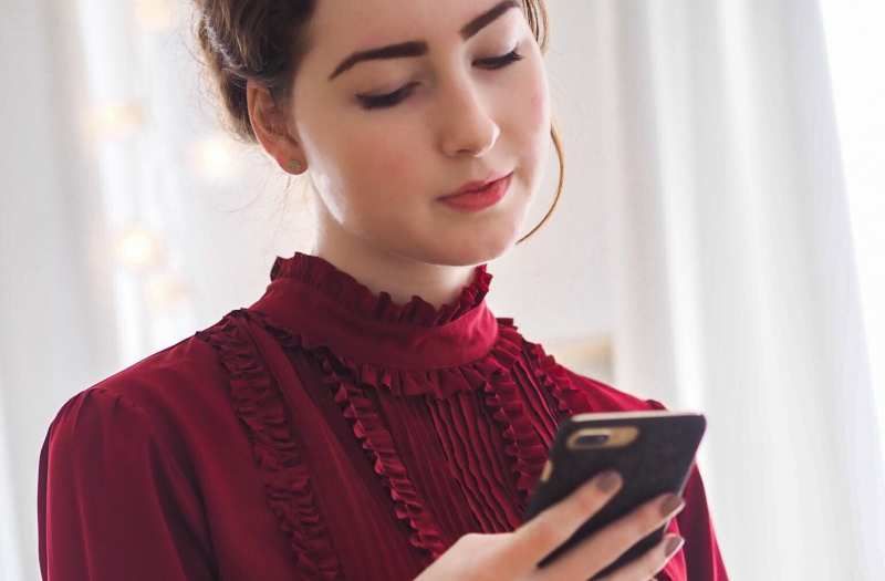 Junge Frau im roten Kleid SMS auf einem Telefon