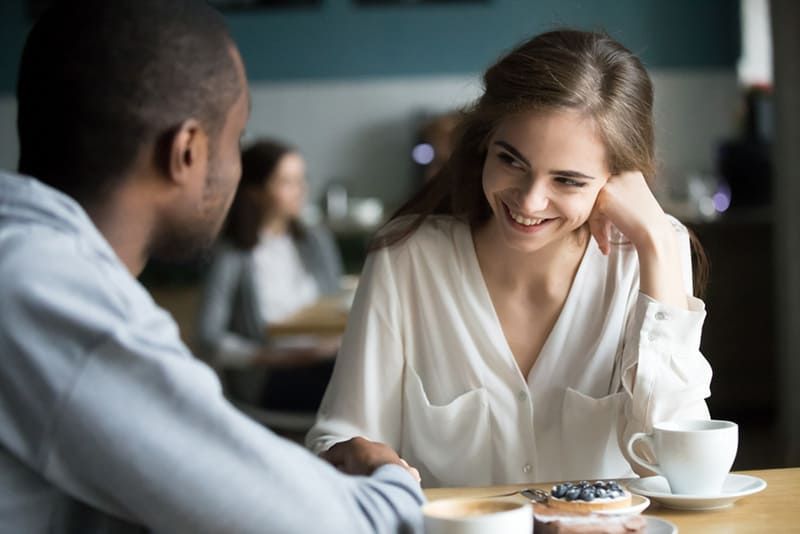 Frau lächelt beim Date mit dem Fingerknöchel am Kiefer