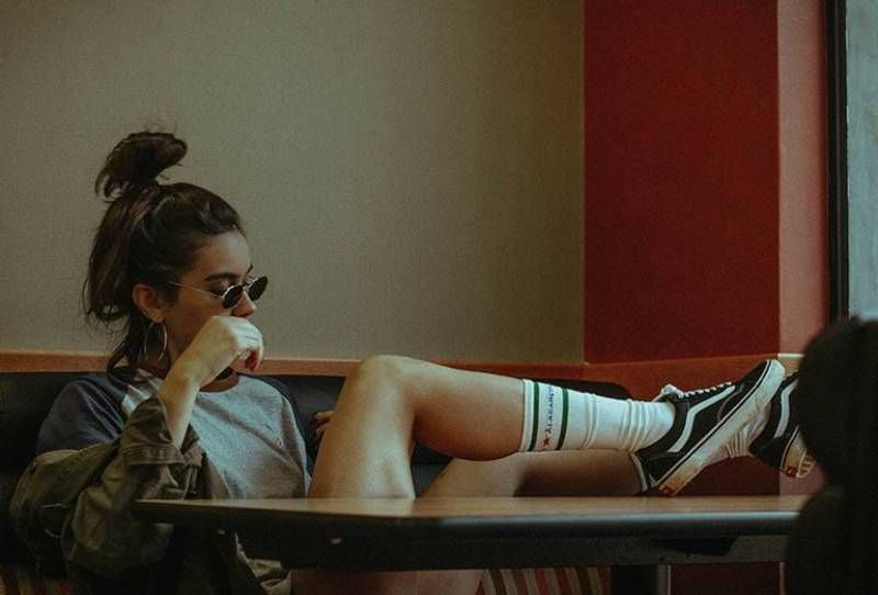 Hipster-Frau legt Beine auf Tisch im Café