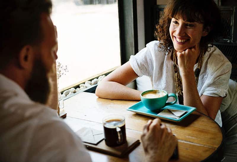 lächelnde Frau, die Mann im Café ansieht