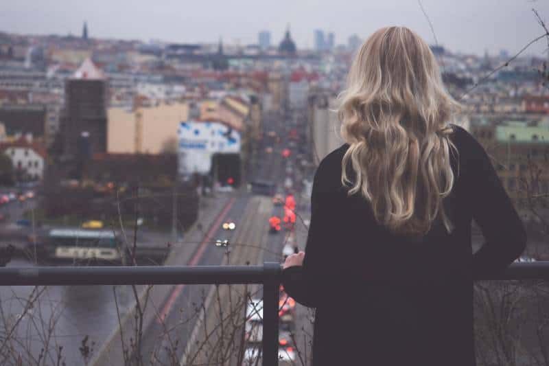 Frau blickt vom Balkon auf die Stadt