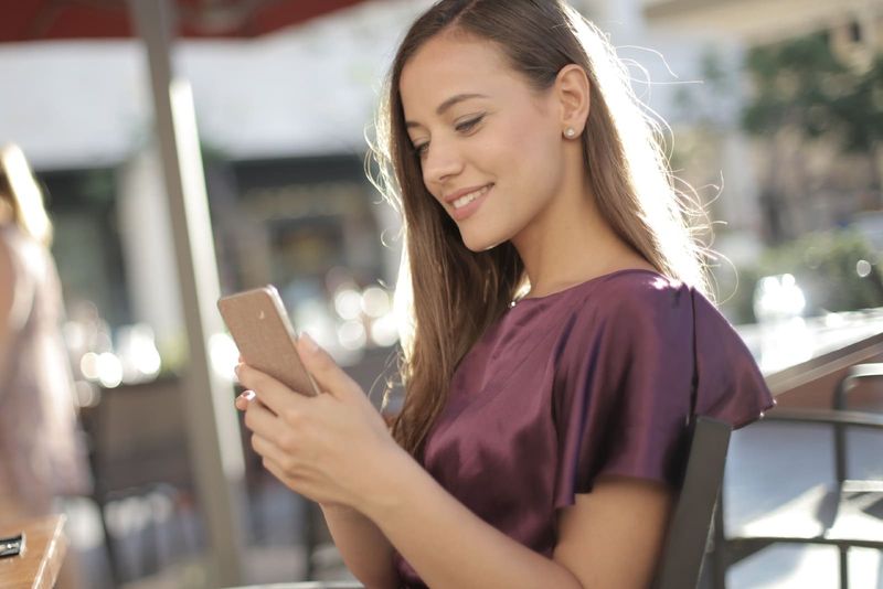 Glückliche Frau in lila Bluse mit Smartphone