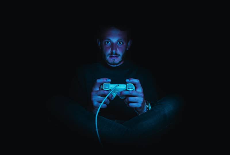 Mann hält Gamecontroller im Dunkeln