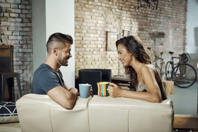 Paar sitzt im Wohnzimmer und unterhält sich beim Kaffee