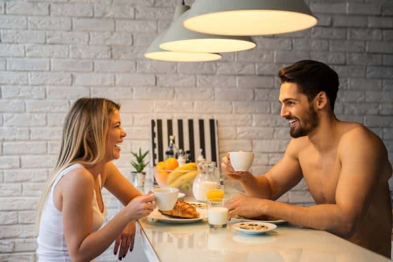 Lächelnder Mann und Frau unterhalten sich, während sie eine Tasse Kaffee halten