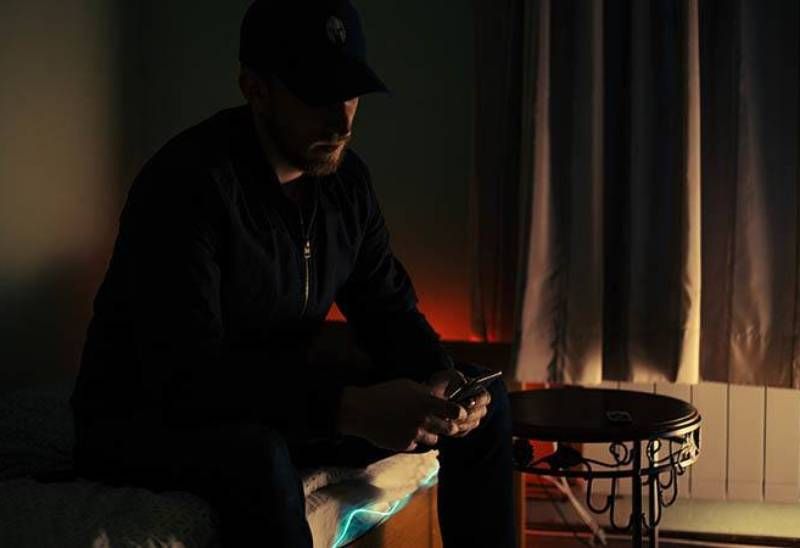 dunkles Foto eines Mannes, der zu Hause auf seinem Telefon tippt