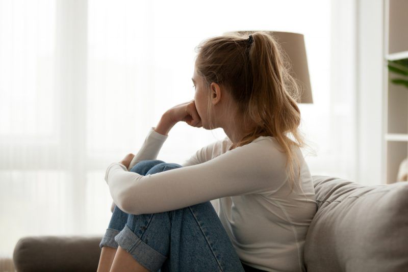 junge traurige Frau sitzt auf der Couch