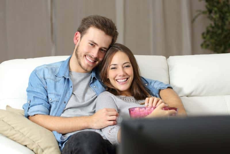 Paar sieht sich einen Film im Fernsehen an und sitzt zu Hause auf einer Couch