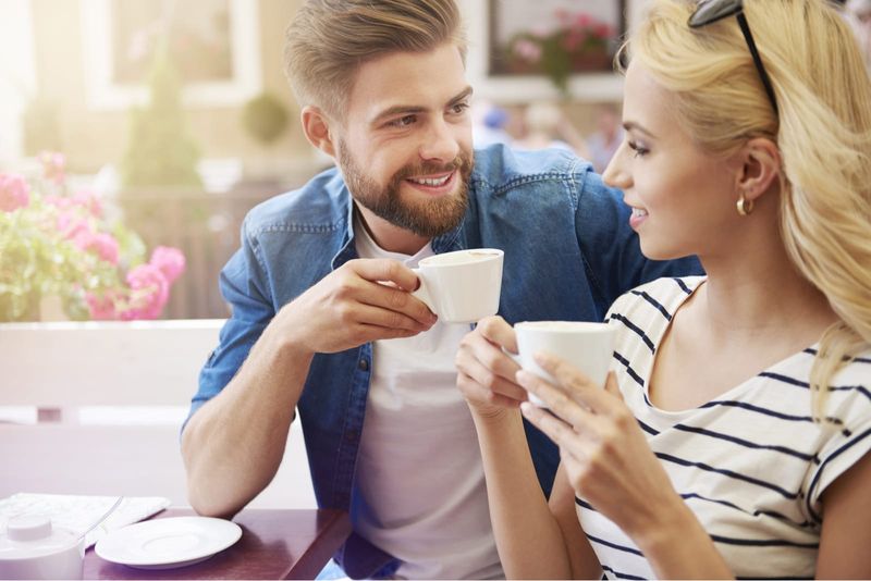 Mann mit Bart trinkt Kaffee und spricht mit Frau