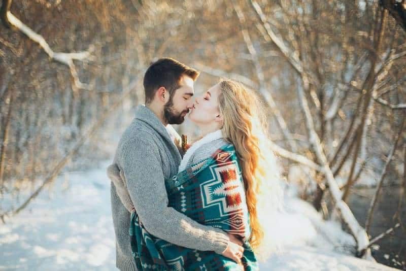 Mann und Frau umarmen sich und wollen sich während der Schneesaison küssen
