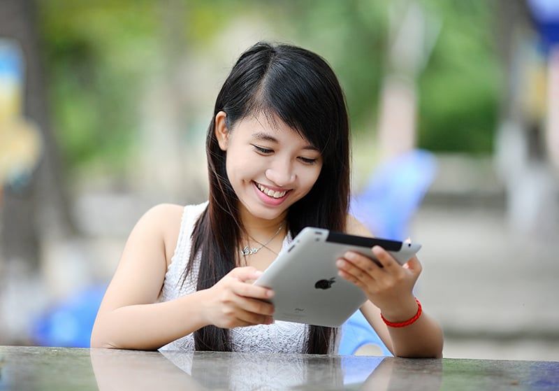lächelnde Frau, die das iPad im Freien hält