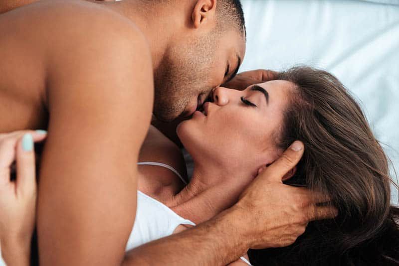 Paar küsst sich mit geschlossenen Augen im Schlafzimmer